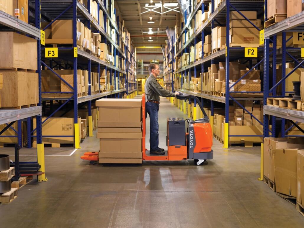 man-on-warehouse-vehicle-driving-boxes-on-cart