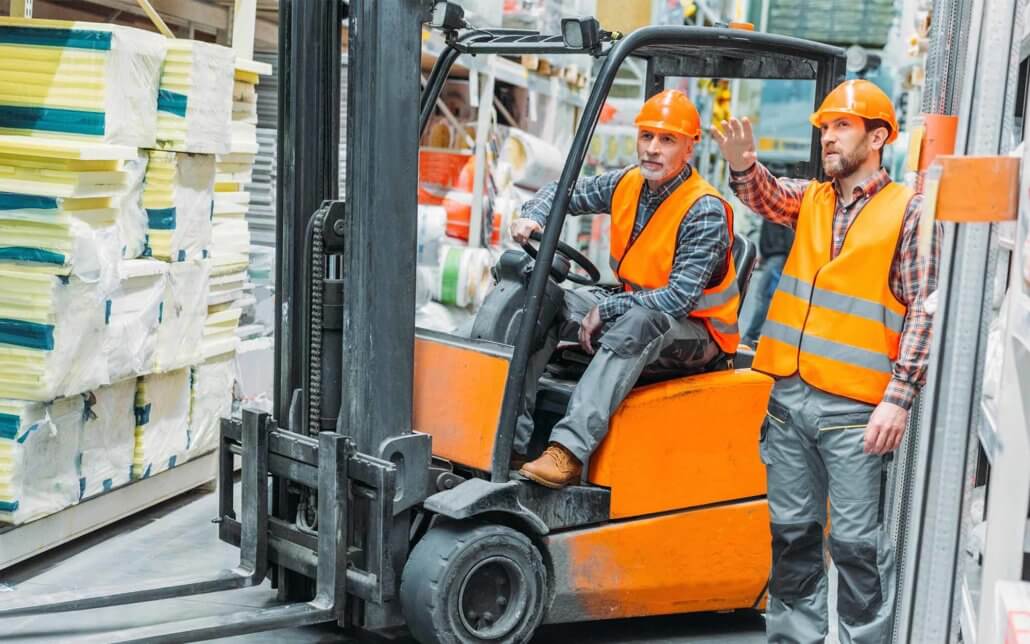 Two men working in a warehouse with a forklift