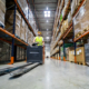 Forklift operator during work in large warehouse drives between shelves